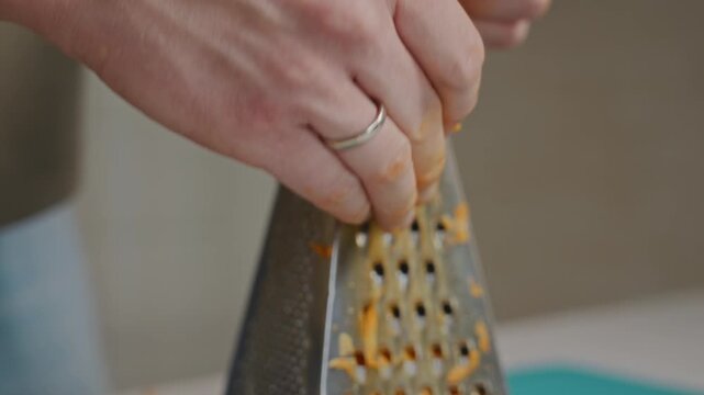 Medium shot of a man finishing grating carrot on a kitchen grater. Final stage of vegetable preparation and everyday home cooking routine without showing face. High quality 4k footage