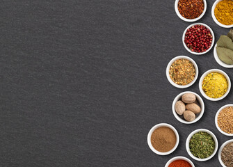 Assorted seasonings and herbs over stone background with copy space