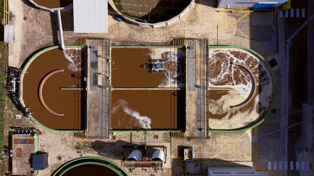 Top-down view of industrial wastewater treatment showing coagulation flocculation, clarifiers, aeration, sludge separation, oil removal, and chemical dosing for metal effluent