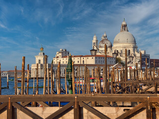 A picturesque view of the iconic Santa Maria della Salute church and Punta della Dogana across the water, framed by a rustic wooden gondola pier in the foreground. © jmag.foto