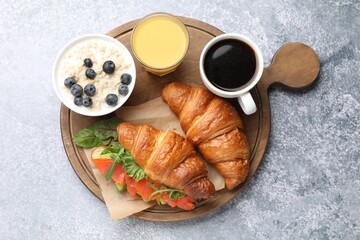 Fototapeta premium Healthy breakfast. Tasty croissant with salmon, juice, coffee and oatmeal on light grey table, top view