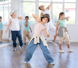 Obraz premium In sports studio, creative childrens team learns hip-hop dance accompanied by experienced man teacher