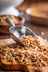 Wholegrain conchiglie pasta on scoop on wooden table.