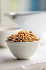 Wholegrain conchiglie pasta in bowl on white table.
