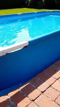 Above-ground swimming pool with blue water and brick patio outdoors