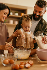 Happy family baking together, adding flour to dough