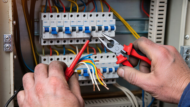 electrician at work, Components being fixed, Connecting power, Panel maintenance, Electrical box, A new electrical component is being installed in the mounting rail, Electrician is fixing the panel, 