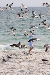 A Child Plays on Gulf Shores Beach While Seagulls Fly Above in Alabama During a Sunny Afternoon