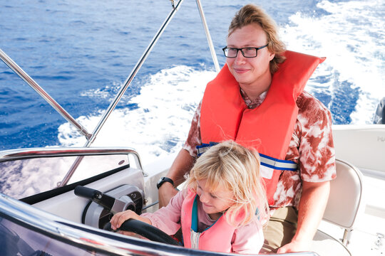 Child Learns to Steer a Boat While Enjoying a Sunny Day at Sea