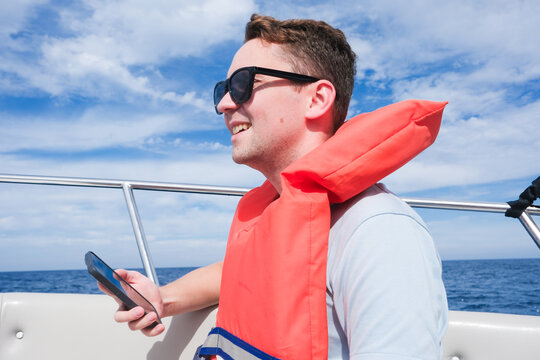 Man in Sunglasses Enjoys Boat Ride While Using Smartphone