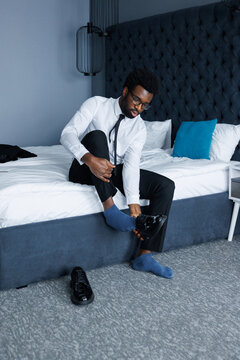 Young serious black businessman or entrepreneur takeoff shoe on bed