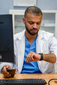 Doctor checking smartwatch and mobile phone for time management