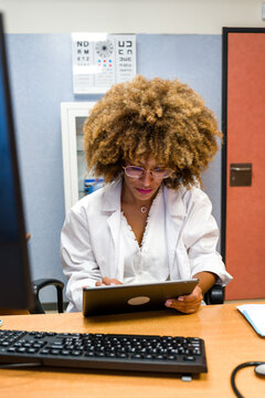 Black doctor using tablet in optometry office