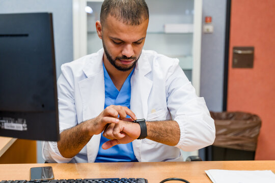 Doctor checking medical data on smartwatch in clinic