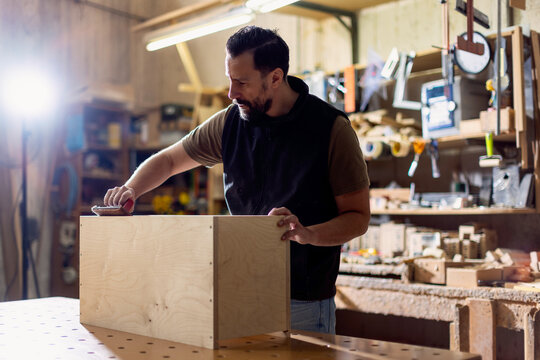Craftsman works on a wooden project in a workshop at night