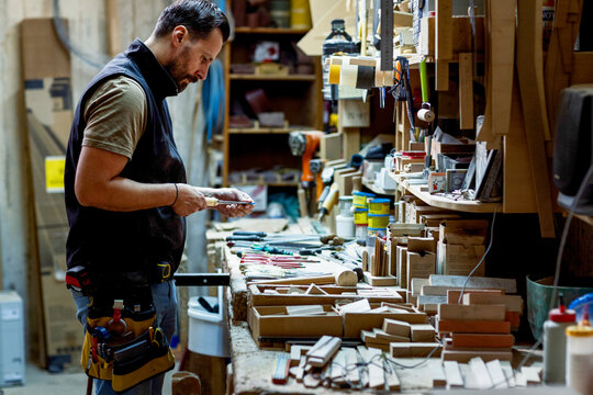 Skilled carpenter crafting wood items in a busy workshop space