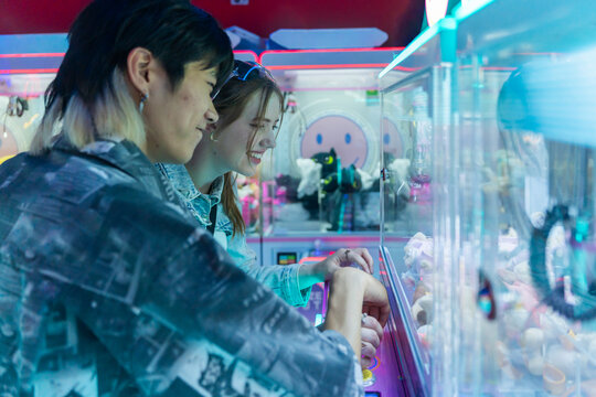 Couple Enjoying Claw Machine Games at an Arcade in the Evening