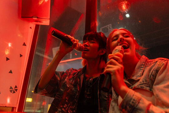 Friends Enjoy Karaoke in a Lively Neon-Lit Room at Night