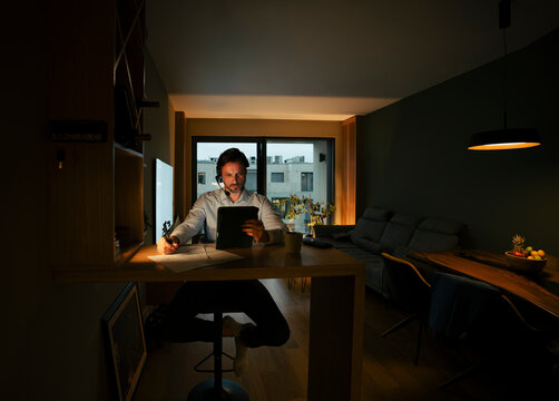 Man working late night home office focused with headset
