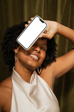 Woman is smiling and holding a smartphone with blank screen