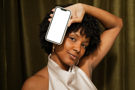 Woman with a smartphone with blank screen smiles in studio