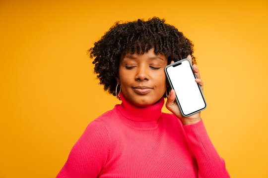 Woman holding a mobile phone with white screen in a studio setting