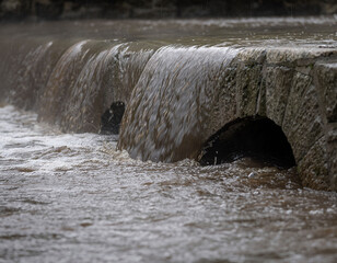 Floodwater overtopping a retaining wall with partially submerged culverts