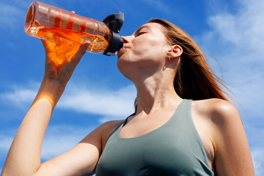 Woman Drinking Water After Workout Under Blue Sky