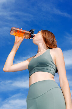 Athletic Woman Drinking Water Under Clear Blue Sky