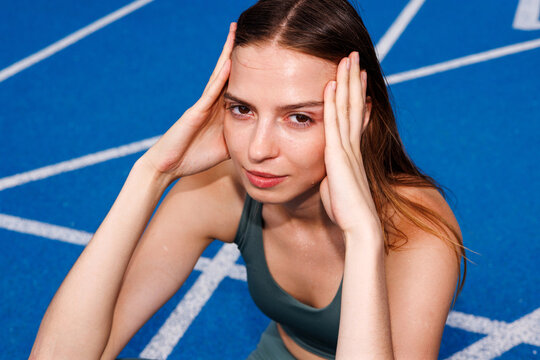 Fitness woman  Tired athlete resting after workout on blue track