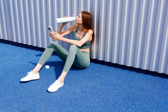 Runner Woman drinking water and checking phone after workout