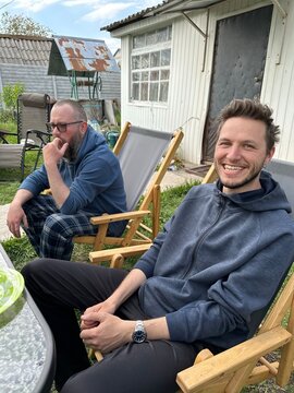 ugc. Two young men sit on folding chairs on the street near a house