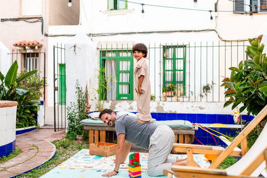 Cheerful child and father playing at home patio