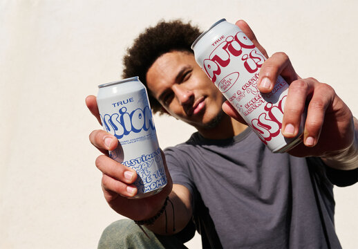 Real photo of Man Holding Two Blank Cans of two sizes. PSD mockup.