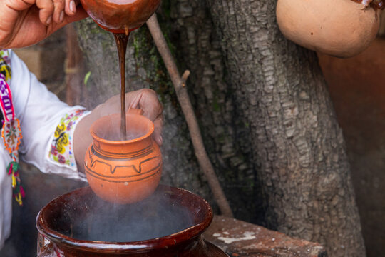 Pouring rich atole with cacao into a traditional pot