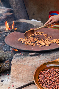 Focused artisan toasting almond over open fire in a comal
