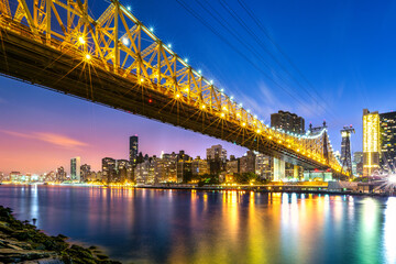 Fototapeta premium Long exposure of Queensboro bridge and its cable car line, at dusk viewed from Roosevelt island, New York