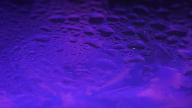 Close-up of a textured surface illuminated with a vibrant purple light, showcasing a rugged terrain with a mix of dark and bright spots in a dramatic lighting effect.