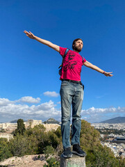 Man standing with arms wide open above city