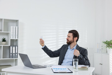 Naklejka premium Man suffering from heat at table near white wall indoors