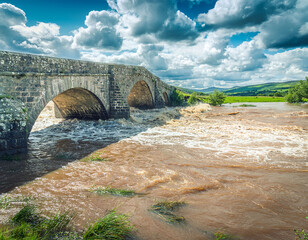Stone bridge in storm and flood with swollen river