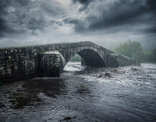 Stone bridge in storm and flood with swollen river