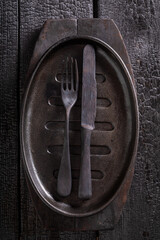 Empty black metal grill plate on burnt table.