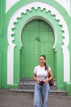 Young woman with camera at green Arabic door in Tangier