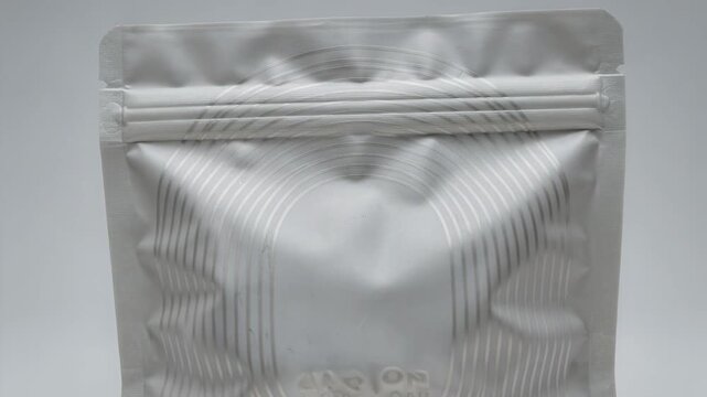 Closeup medium shot focusing on curved laser scoring patterns on a flexible pouch demonstrating innovative design for easy grip and tear functionality.