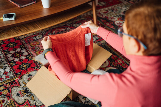 Middle-aged adult woman opening clothing delivery box