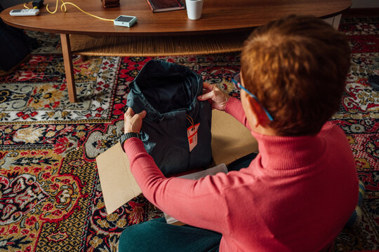 Middle-aged adult woman opening clothing delivery box
