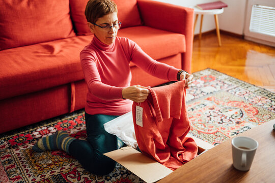 Middle-aged adult woman opening clothing delivery box