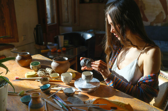 A woman with a cat is drinking tea by the window