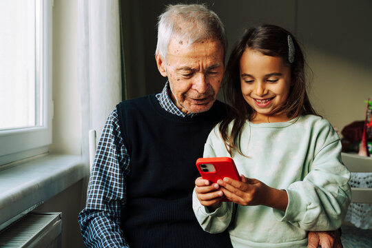 Senior man and little girl looking at mobile phone screen